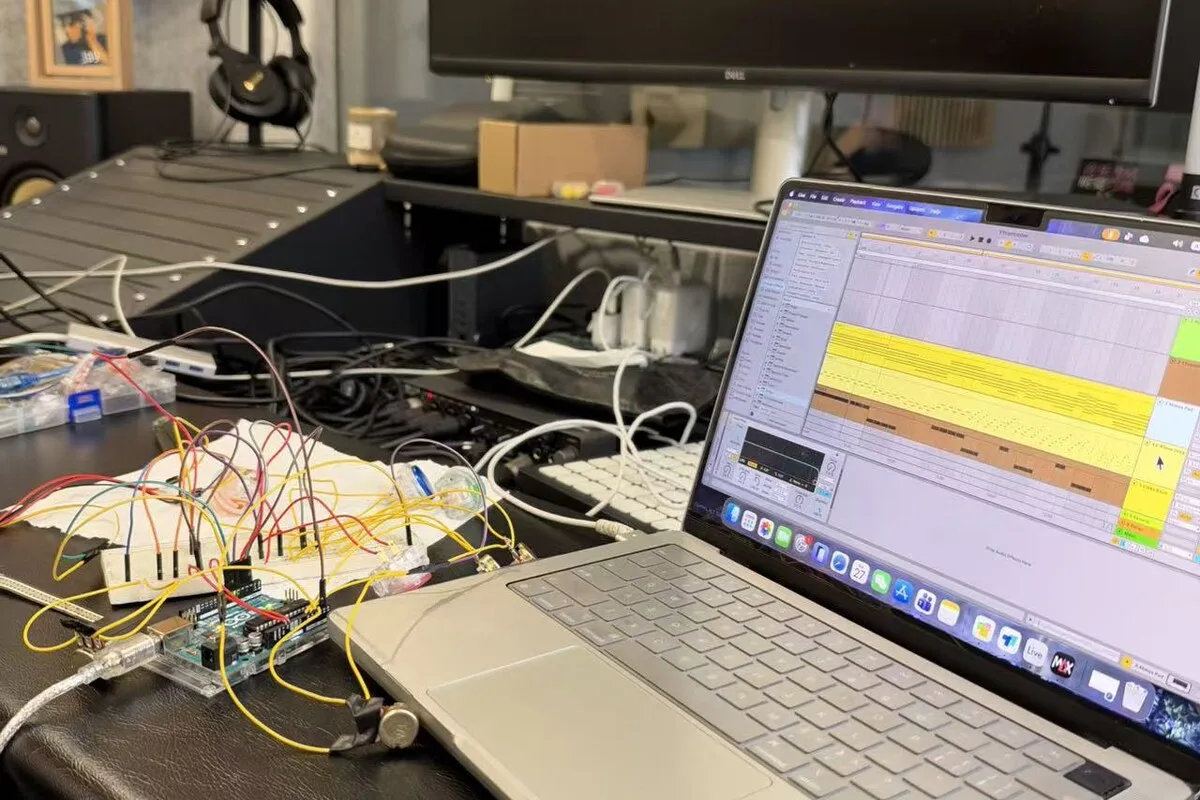 Breadboard prototype with coloured jumpers connected to a laptop running Ableton Live.